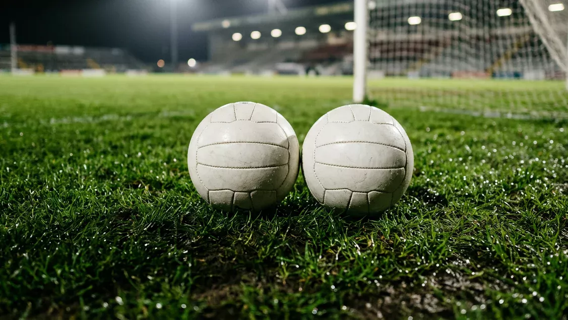 Dos balones de fútbol sobre el césped verde de un campo iluminado cerca de una portería