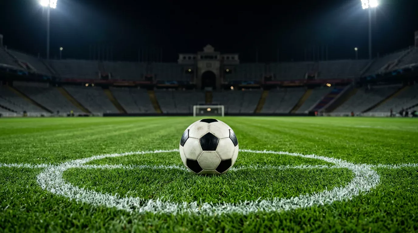 Balón de fútbol blanco y negro en el centro del círculo de un campo de fútbol iluminado de noche